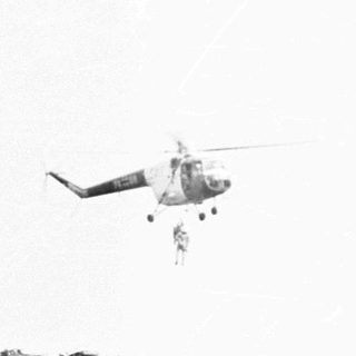 Helicopter and military vehicle on a grassy field.