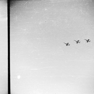 Four airplanes fly in formation across a cloudy sky.