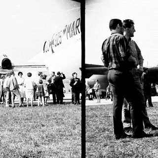 Group of people observing an airplane on a grassy field.