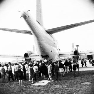 Crowd gathers to view a large airplane on the ground.