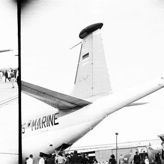 A Marine transport plane on a runway with onlookers.