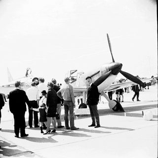 Group examining a German aircraft on an airfield.