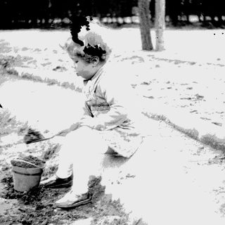 Here's a brief summary of the image: Child playing with a pail and shovel outdoors.