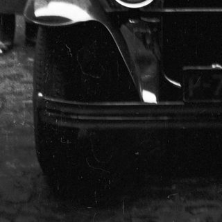 Vintage car with a driver, partially visible in black and white.