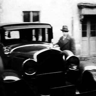 Vintage car and man standing near a building.