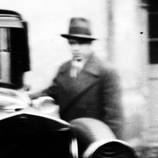 Vintage car and man standing near a building.