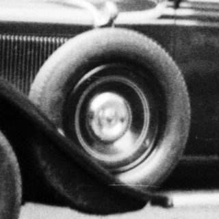Man stands next to a vintage car near a building.