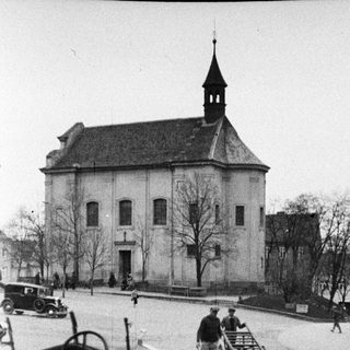 Vintage car near a church and people in a square.