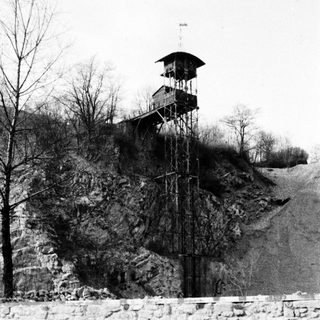 Watchtower stands atop a hill, overlooking a stone wall.