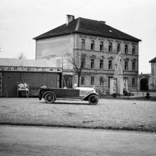 Vintage car in front of a building with signage.