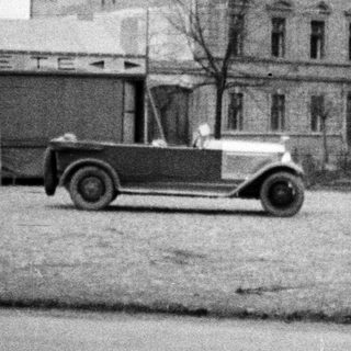 Vintage car in front of a building with signage.