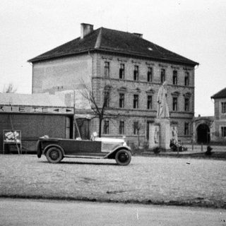 Vintage car in front of a building with signage.