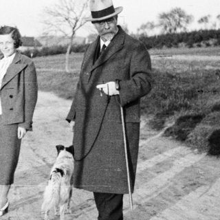 Three people and a dog walk along a country road.