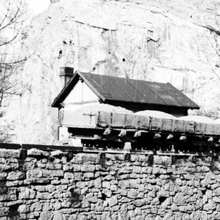 Church atop a rocky hill, viewed from a stone wall.