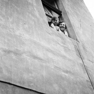 Children peering from a window in a textured wall.