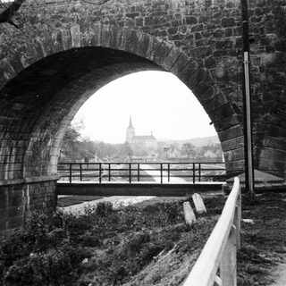 Arched bridge frames a view of a distant church.