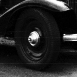 Vintage car and man standing beside it on a road.