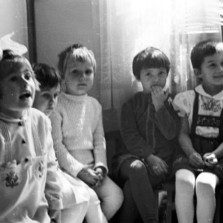 Group of children seated, looking upwards in a black and white photo.