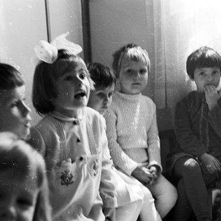 Group of children seated, looking upwards in a black and white photo.