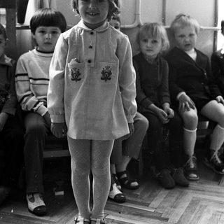 Group of children in a classroom, one standing in front.
