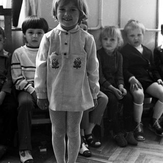 Group of children in a classroom, one standing in front.