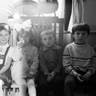 Five children sit together in a black and white photograph.
