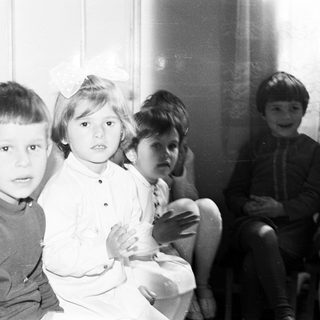 Group of children sitting together in a black and white photo.