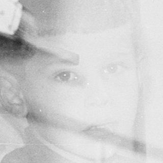 Here's a brief summary of the image: Children peering through a window, appearing ghostly and blurred.