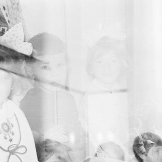 Here's a brief summary of the image: Children peering through a window, appearing ghostly and blurred.