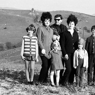Family poses on a hill with a ski lift in background.