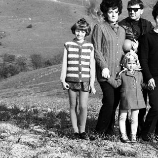Family poses on a hill with a ski lift in background.