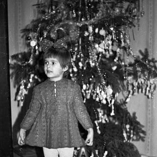 Black and white photo of a child near a Christmas tree.