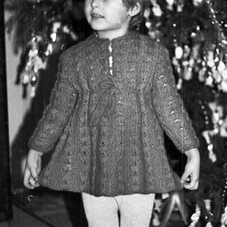 Black and white photo of a child near a Christmas tree.
