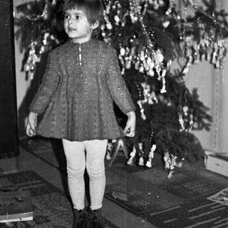 Black and white photo of a child near a Christmas tree.