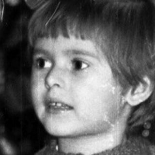 Black and white photo of a child near a Christmas tree.
