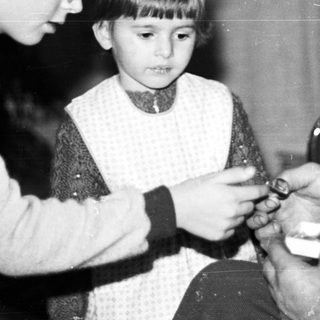 Boy and older man affixing a hat to a child.