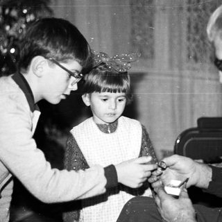 Boy and older man affixing a hat to a child.
