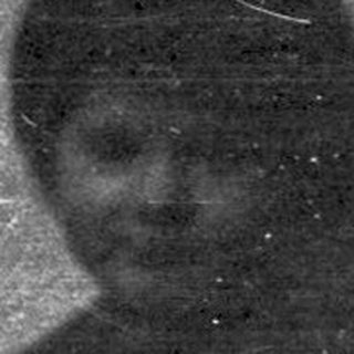 Here's a brief summary of the image: A dark, grainy image shows a person near a machine.