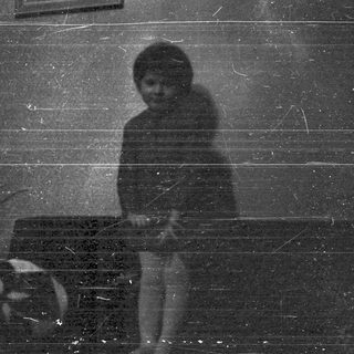 Here's a brief summary of the image: A dark, grainy image shows a person near a machine.