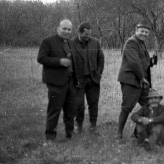 Group of men outdoors, one taking a photo.