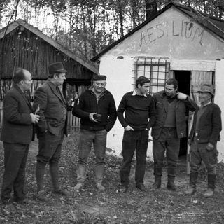 Group of men standing near a building with "Aesilium" written above.