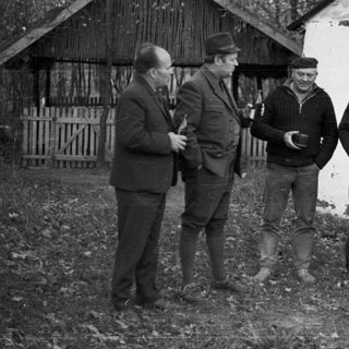 Group of men standing near a building with "Aesilium" written above.