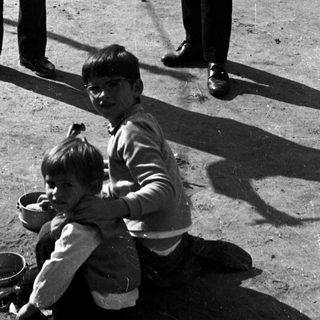 Musician plays violin while a boy watches, seated.