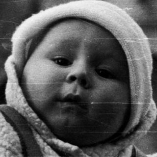 Baby in a stroller, looking upwards with an umbrella.