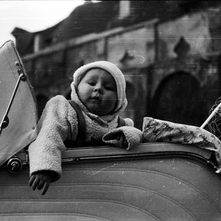 Baby in a stroller, looking upwards with an umbrella.