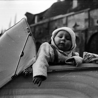 Baby in a stroller, looking upwards with an umbrella.