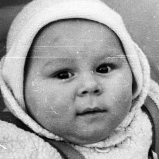 Baby in a vintage stroller, looking directly at the camera.
