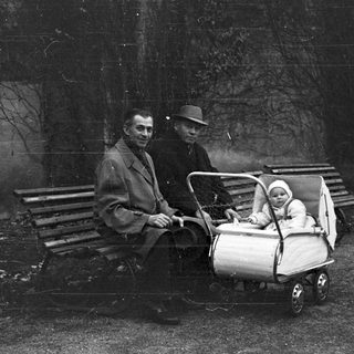 Men and baby in a vintage stroller outdoors.