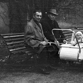 Men and baby in a vintage stroller outdoors.