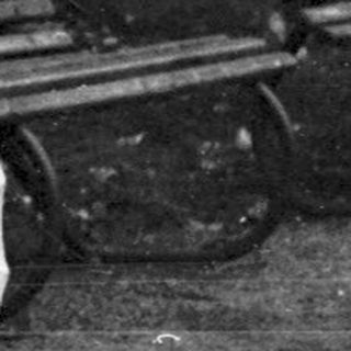 Men and baby in a vintage stroller outdoors.